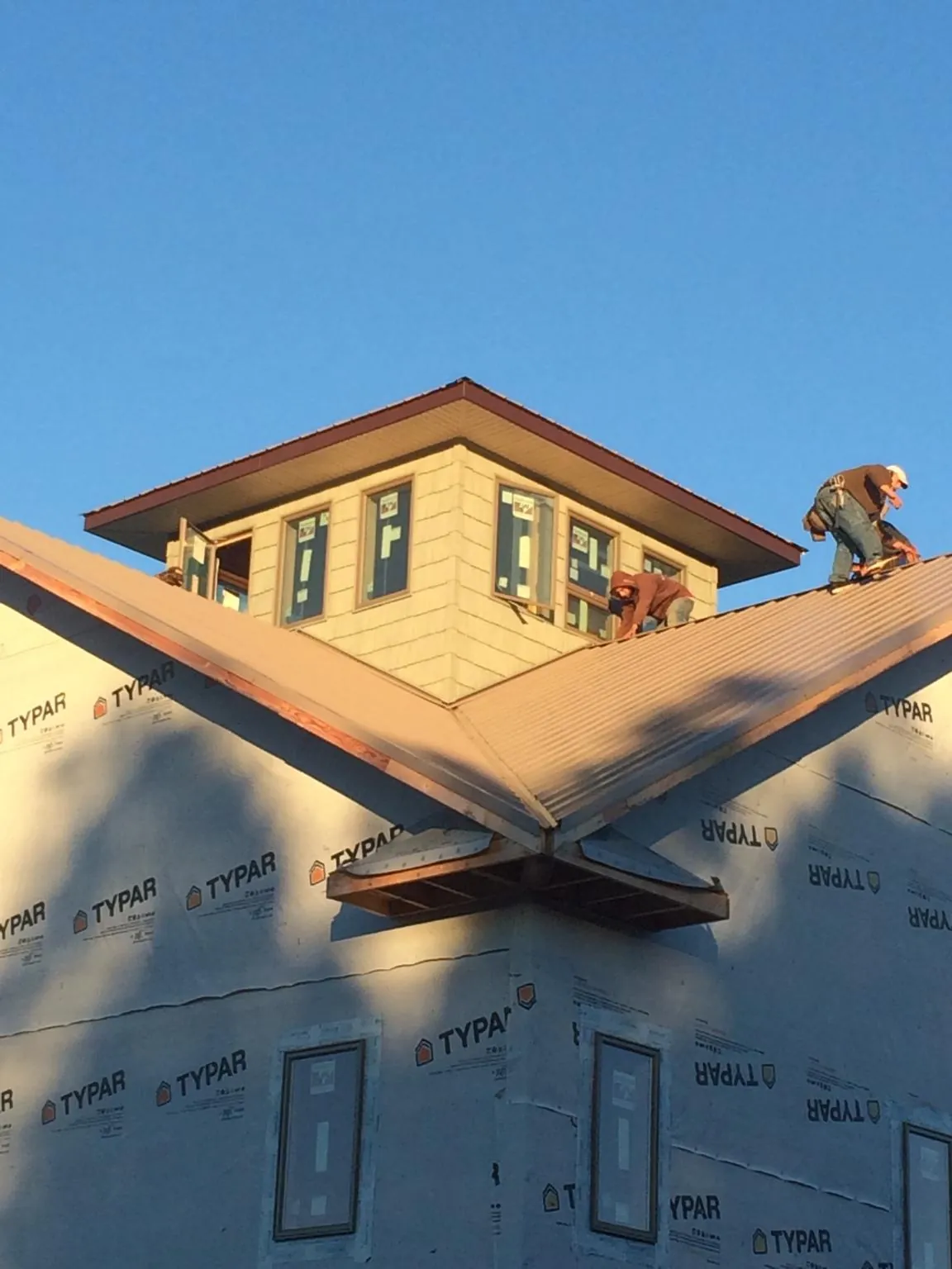 Roofers working around a rooftop cupola on a new metal roof at sunset — Roof Waterproofing in Clewiston by Roofing Brothers